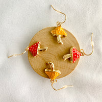 gold-toned enamel mushroom earrings that come in red or yellow
